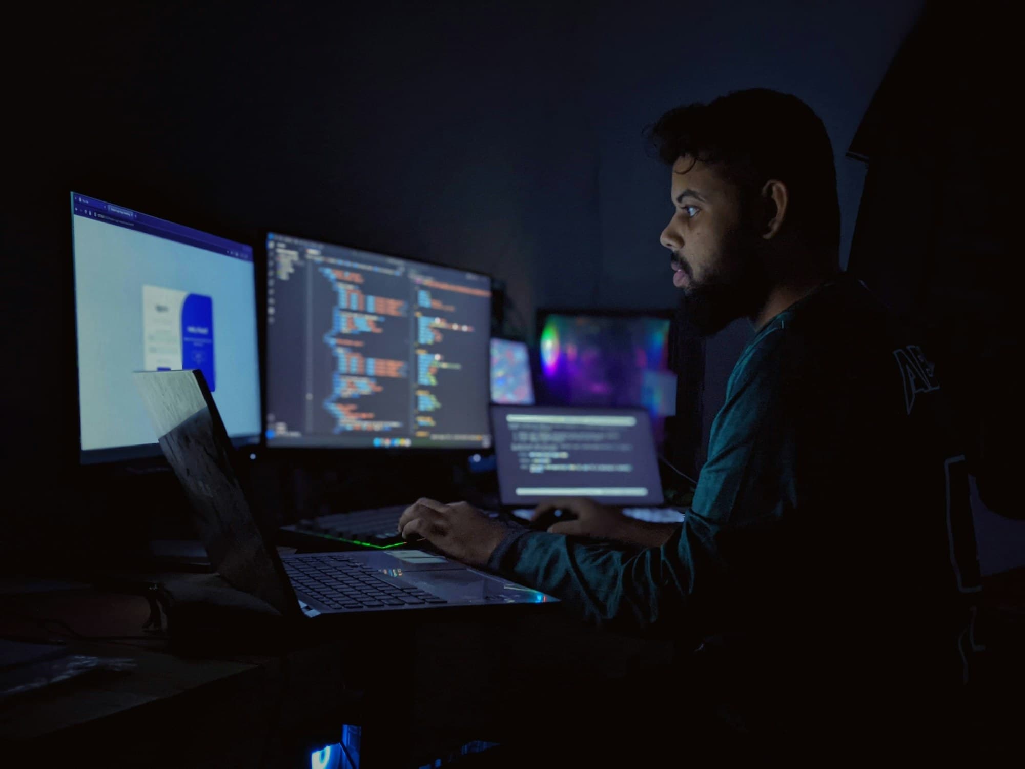 Développeur travaillant de nuit devant plusieurs écrans de code
